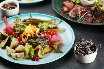 Assorted Pickled vegetables plate on dark concrete background closeup.
