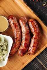 Top view on three grilled sausages on wooden board