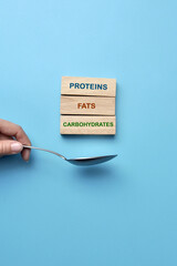 Wooden cubes with inscriptions: proteins, fats, carbohydrates. The balance of proteins, fats and...