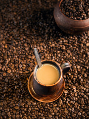 A cup of aromatic coffee with milk on the background of coffee beans.