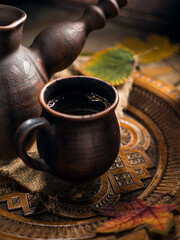 Ceramic cup with aromatic coffee brewed in a Turk surrounded by autumn leaves.