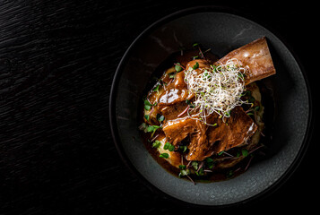 beef rib with mashed potatoes on plate on rustic wooden table dark background