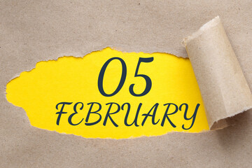 february 05. 05th day of the month, calendar date.Hole in paper with edges torn off. Yellow background is visible through ragged hole.Winter month, day of the year concept