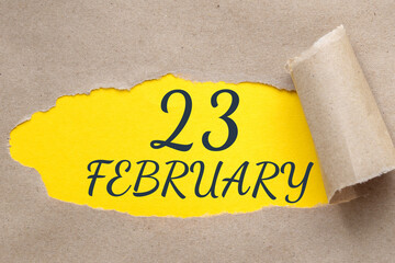 february 23. 23th day of the month, calendar date.Hole in paper with edges torn off. Yellow background is visible through ragged hole.Winter month, day of the year concept