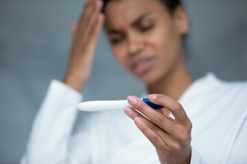 Close up focus on plastic test in female hands, unhappy frustrated young african ethnic woman...