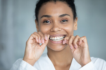 Close up head shot happy pretty young african american mixed race woman in bathrobe cleaning teeth...