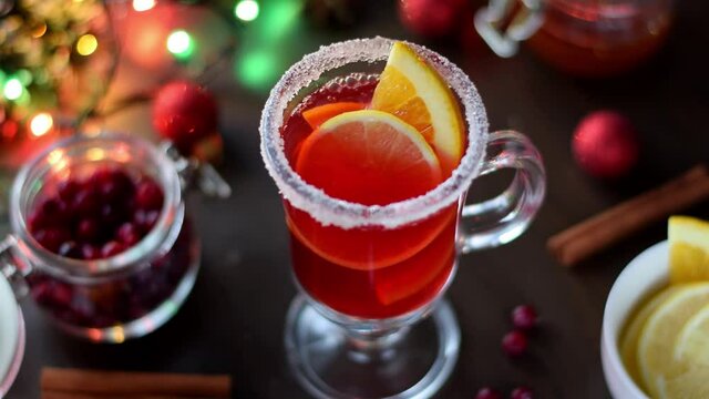 Adding slice of lemon into mulled wine in the Irish glass with sugar border. Serving hot Christmas drink. Festive table setting