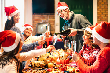 Millenial friends on santa hats celebrating Christmas with champagne and sweets food at log cabin -...