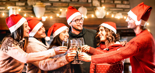 Young friends with santa hats celebrating Christmas with champagne wine toast at home reunion -...