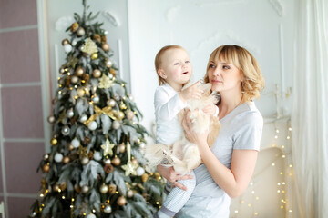 Child and mother in light pajamas on the background of a Christmas tree