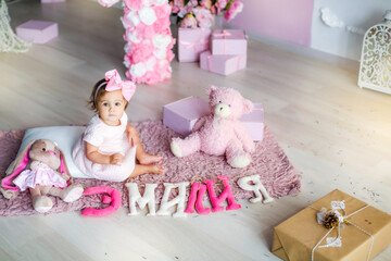 Fototapeta na wymiar Baby with a pink dress on a background of pink adornment with a pink bow on her head