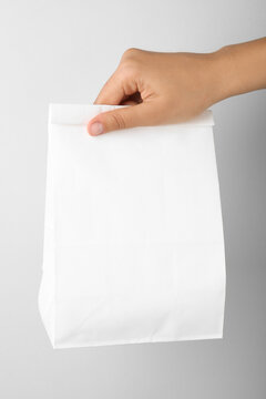Woman holding paper bag on white background, closeup