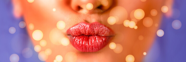 Close up of female mouth sending a blowing kiss with bokeh lights on purple blue background....