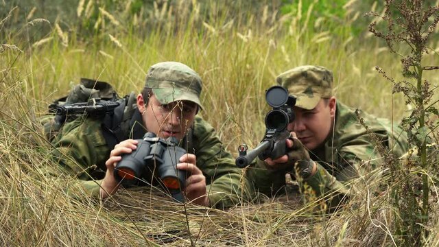 sniper with a gunner are sitting in ambush in the bushes