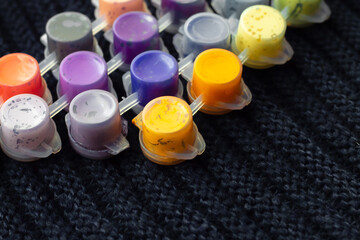 jars with liquid for drawing and painting inside on a woolen black background in soft focus for the design of children's creative websites; letters and words can be inserted into the barrels
