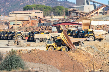 Mining trucks and machinery in Corta Atalaya open mine pit. Deep excavation of pyrite and extraction of minerals of cooper and gold in municipality of Minas de Riotinto, Huelva, Andalusia, Spain