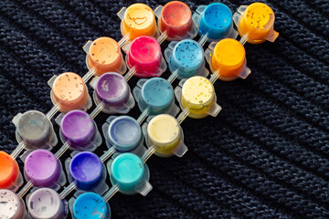 barrels with paints for drawing and painting inside on a woolen black background in soft focus for the design of children's creative websites; letters and words can be inserted into containers