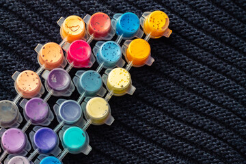 jars with paints for drawing and painting inside on a woolen black background diagonally in soft focus for the design of children's creative websites; letters and words can be inserted into the jars