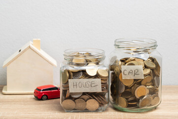 Coin in a glass jar for saving money with house and car