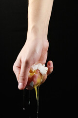 crushed egg with one hand on a black background