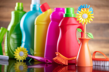 Autumn cleaning. Colorful set of bottles with clining liquids and colorful cleaning kit on brown...