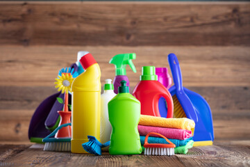 Autumn cleaning. Colorful set of bottles with clining liquids and colorful cleaning kit on brown background.
