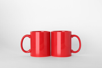 Blank red ceramic mugs on light background