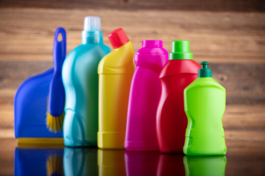 Autumn cleaning. Colorful set of bottles with clining liquids and colorful cleaning kit on brown background.
