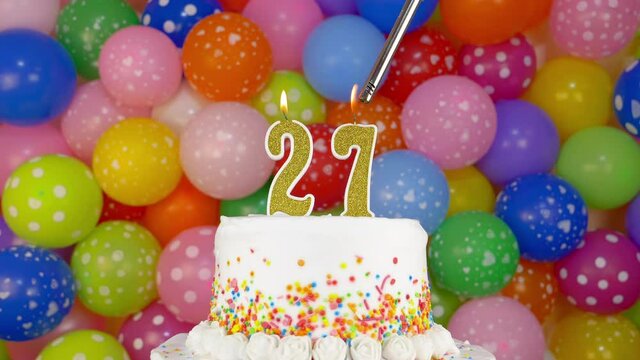 Birthday cake with candles number 27. Cake on a bright festive background of colorful balloons.