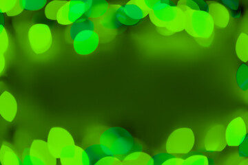 Defocused green lights over dark background. Natural bokeh and bright green lights. Magic background with bokeh. Space for text.