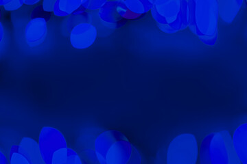 Defocused blue lights over dark background. Natural bokeh and bright blue lights. Magic background with bokeh. Space for text.