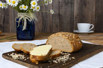 Homemade sliced bread with butter on dark cutting board on wooden table