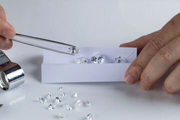 Close up of diamond expert's hand at workplace evaluating gemstones polished diamonds. High quality...