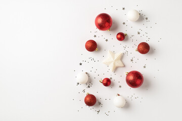 Top view photo of red and white christmas tree decorations star balls and silver confetti on isolated white background with copyspace