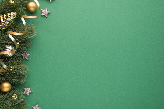 Top view photo of gold and silver christmas tree balls toy cone shiny stars small bells and serpentine on pine twigs on isolated green background with copyspace
