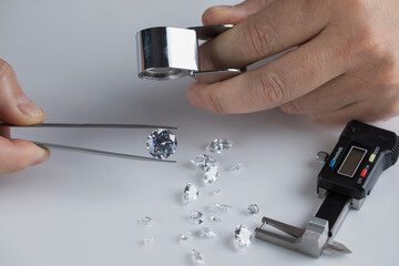 Close up of diamond expert's hand at workplace evaluating gemstones polished diamonds. High quality photo