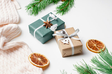 Fototapeta na wymiar Decorated christmas gift boxes with dry oranges and pine tree branches on white