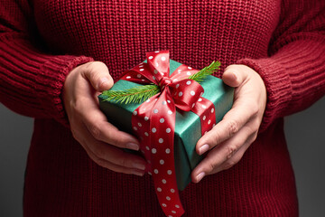 Female hands holding decorated christmas gift box with red bow