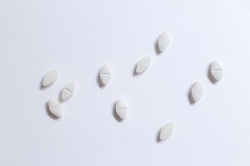scattered white pills on white reflective background