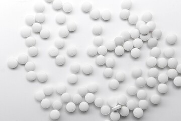 scattered white pills on white reflective background