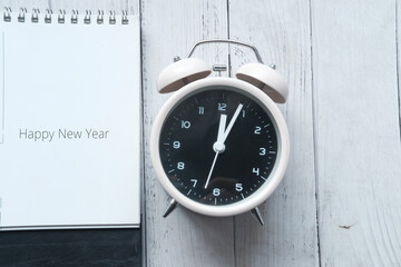 happy new year text on calendar with clock on table 