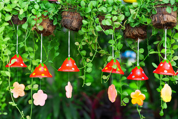 green ivy with red strawberry wind chime tile or small bell hangs in the garden without people and...