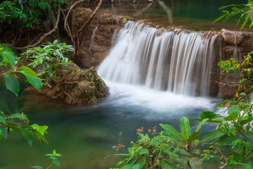 natural waterfall on stream with clear green emerald water and rock for relax with trees and root in the jungle or forest at Huay Mae Khamin waterfall for nature landscape and fresh background