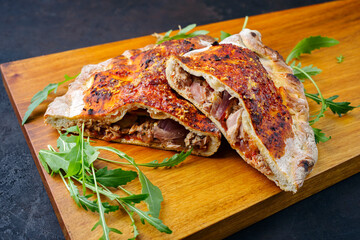 Traditional Italian pizza calzone with tuna fish and onions served as close-up on a wooden design...