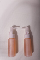 Two mockup bottles with cleansing foam, care cosmetics beige gentle pink containers, face skin washing, anti-age, anti-acne, exfoliating, toner