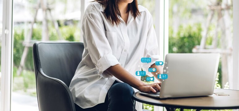 Portrait of woman relax use digital technology social communication with laptop computer.Young asian girl working and typing on keyboard with icon online social media and e-mail at cafe