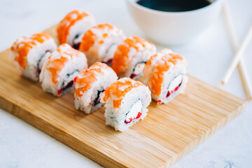 Tasty shrimp rolls on bamboo board with soy sauce, close up. Japanese food