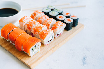 Sushi rolls set on bamboo board, Philadelphia, shrimp rolls and maki with soy sauce, Japanese food.