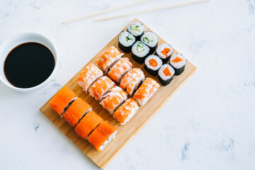 Sushi rolls set on bamboo board, Philadelphia, shrimp rolls and maki with soy sauce, Japanese food.