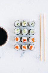 Tasty maki rolls on white background with soy sauce. Japanese food, top view